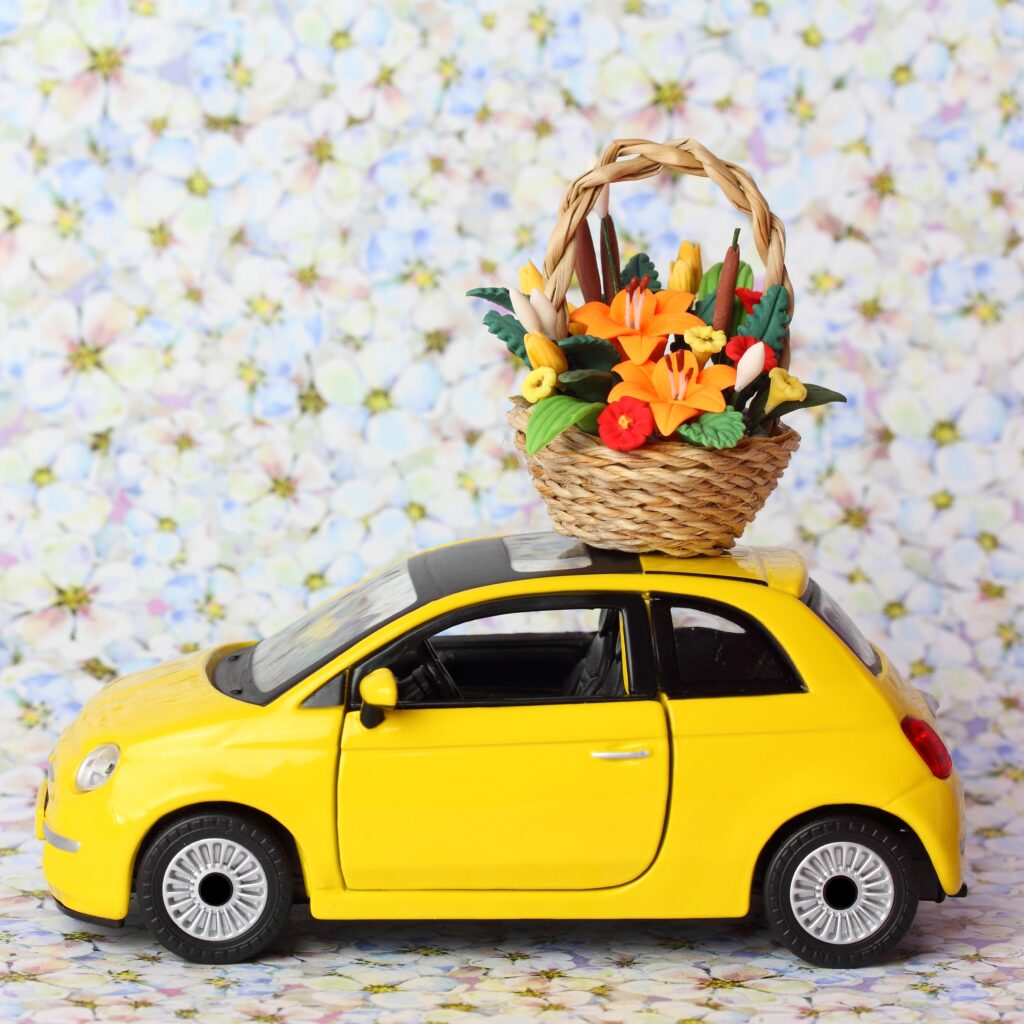 Yellow toy car with mini basket of flowers on the roof.