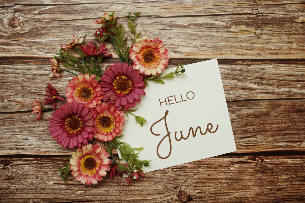 Floral arrangement on wooden boards with postcard inscribed 'Hello June'